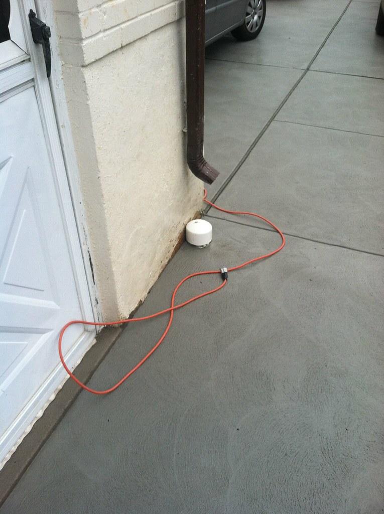 Freshly troweled concrete driveway curing in front of a home's garage